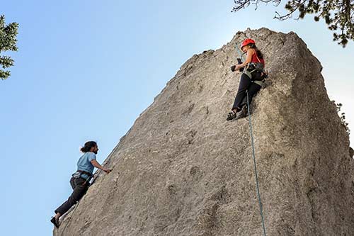 Zwei Personen klettern gesichert einen Felsen hinauf